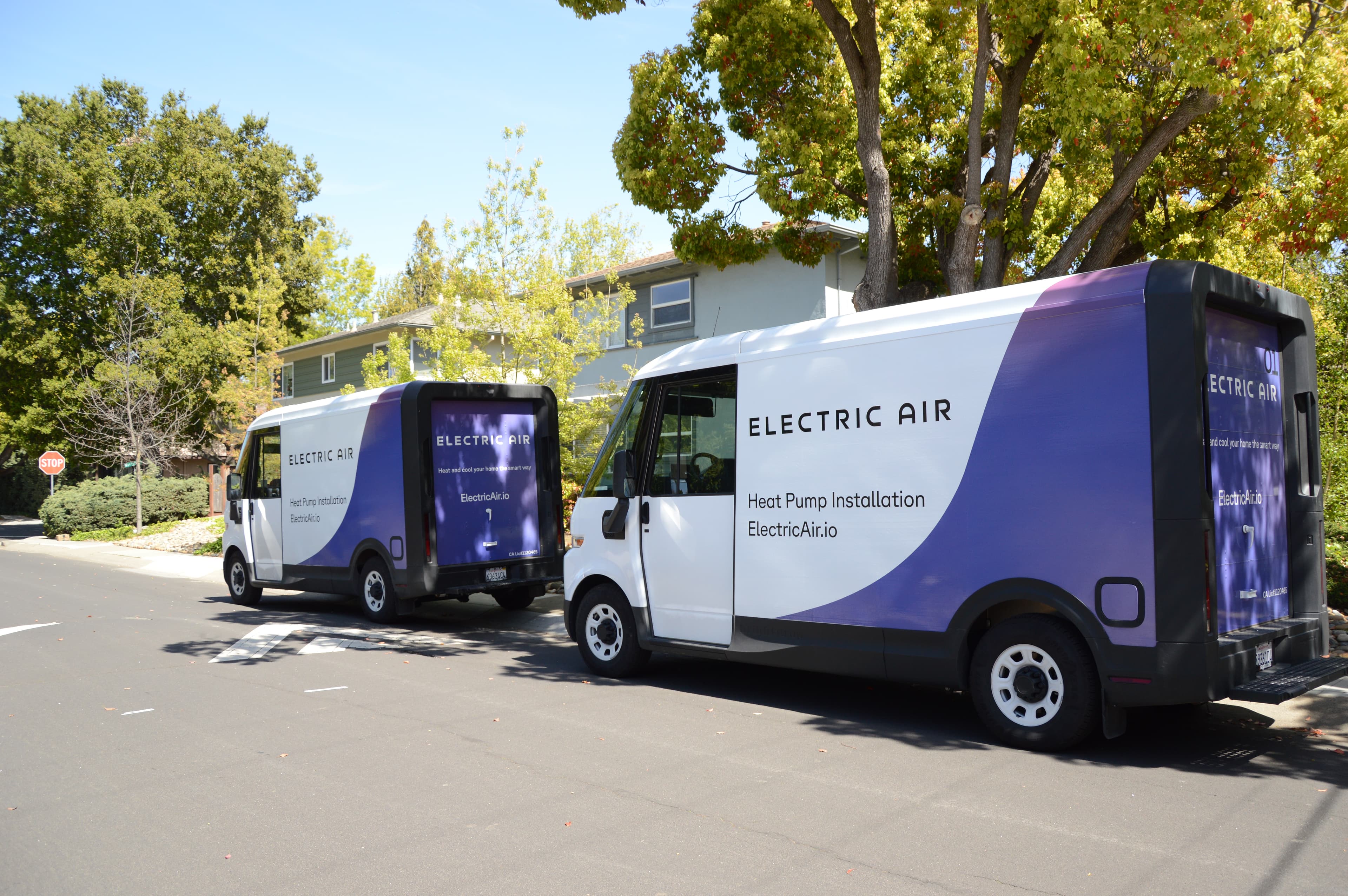 Electric Air branded installation vans parked outside a home